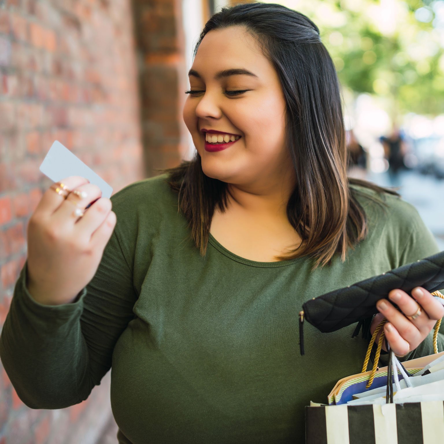 Woman-smiling-holding-her-debit-card-that-earns-her-rewards-and-cash-back.