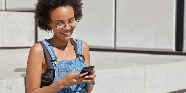 Teen-exploring-Allegiance-financial-resources-on-her-phone-on-steps-outside-in-the-sun.