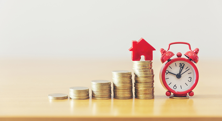 Coins stacked up by a House and Clock Figurine 