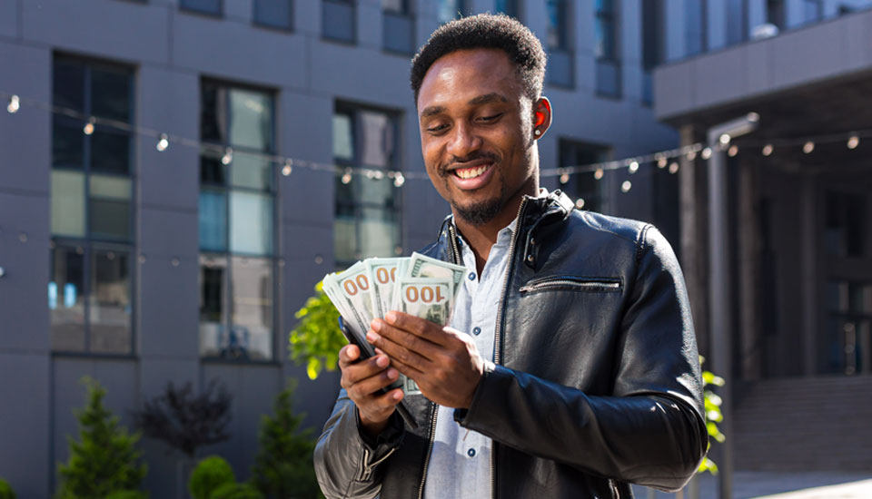 Man in leather jacket holding his money he got from a personal loan or payday loan in hand.
