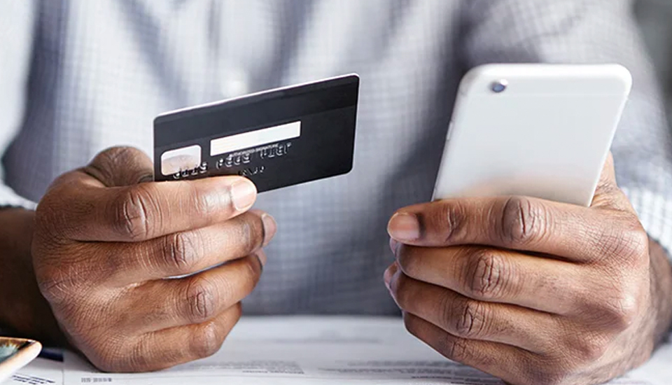 person holding credit card and cell phone