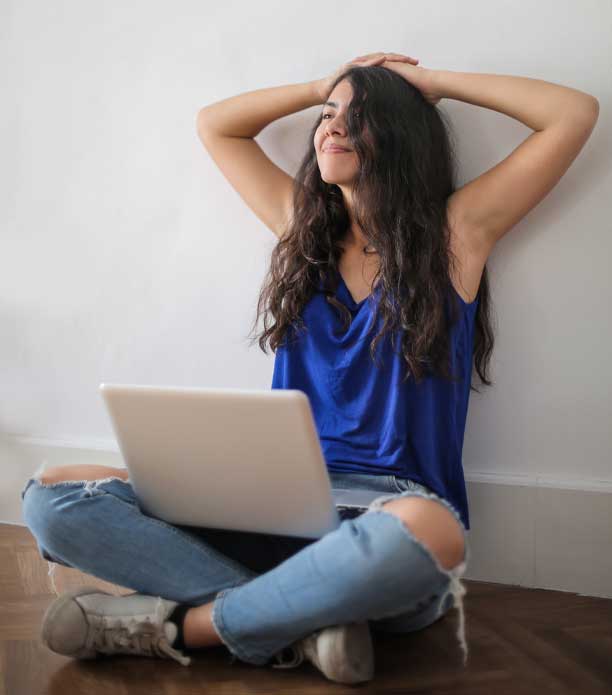 woman with hands on head and computer in lap