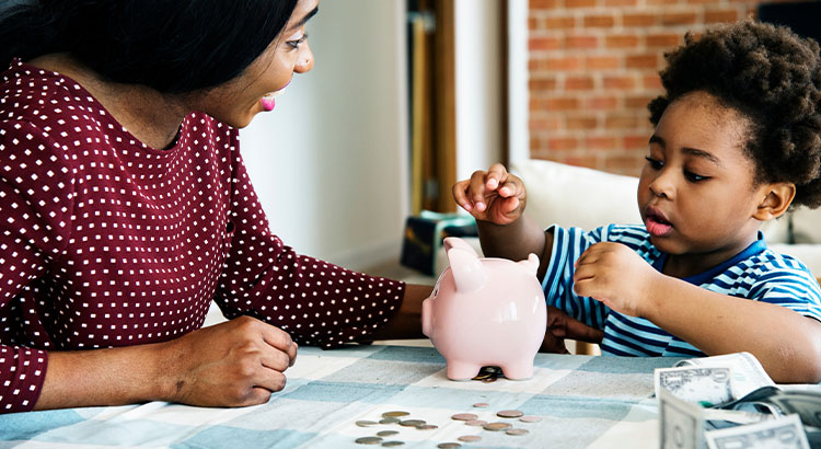 Mother and son putting money into piggy bank.