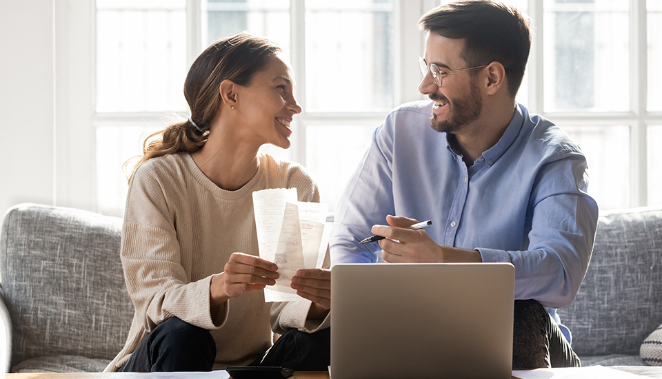 couple smiling at each other while working on monthly budget