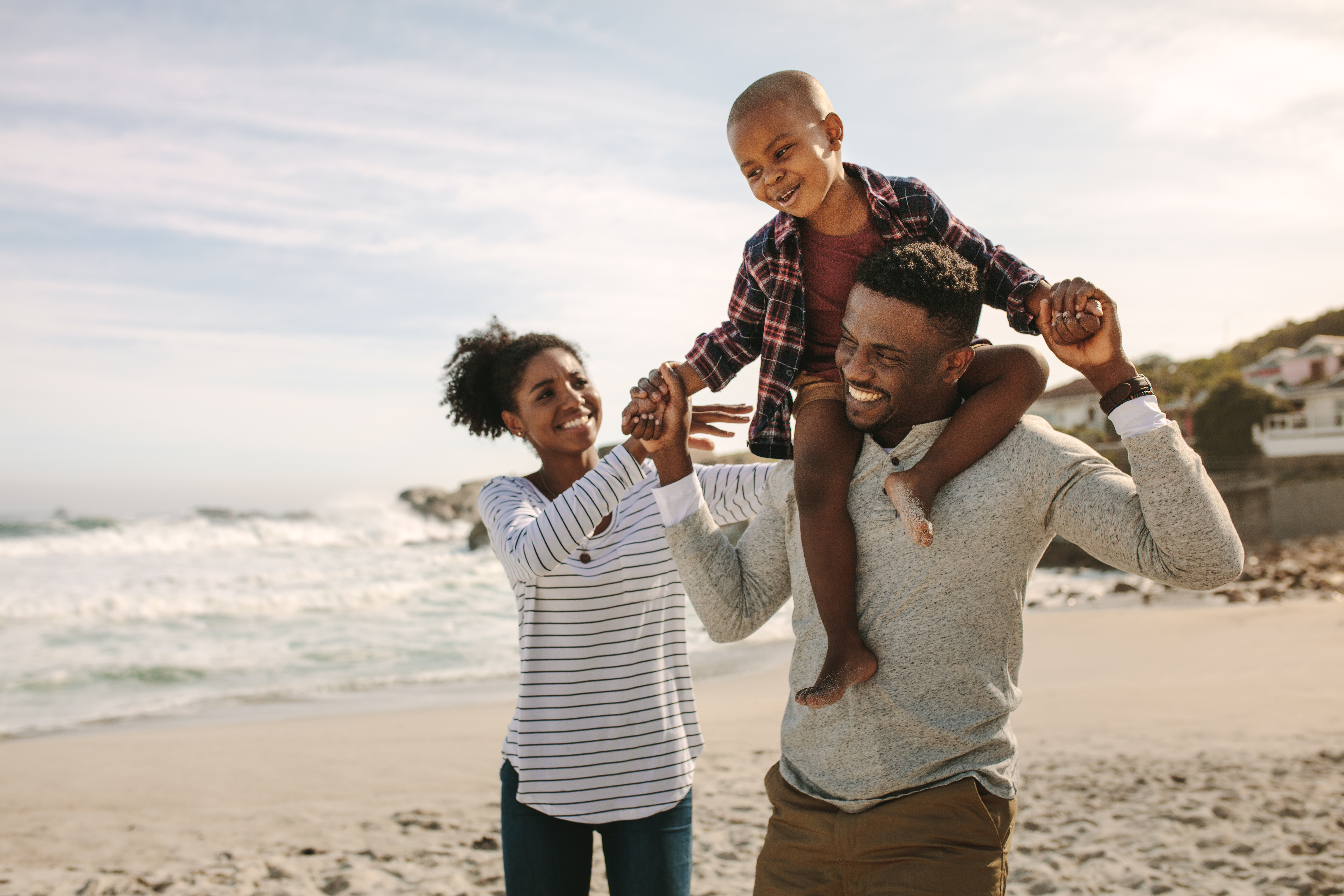 man, woman and son are walking on the beach