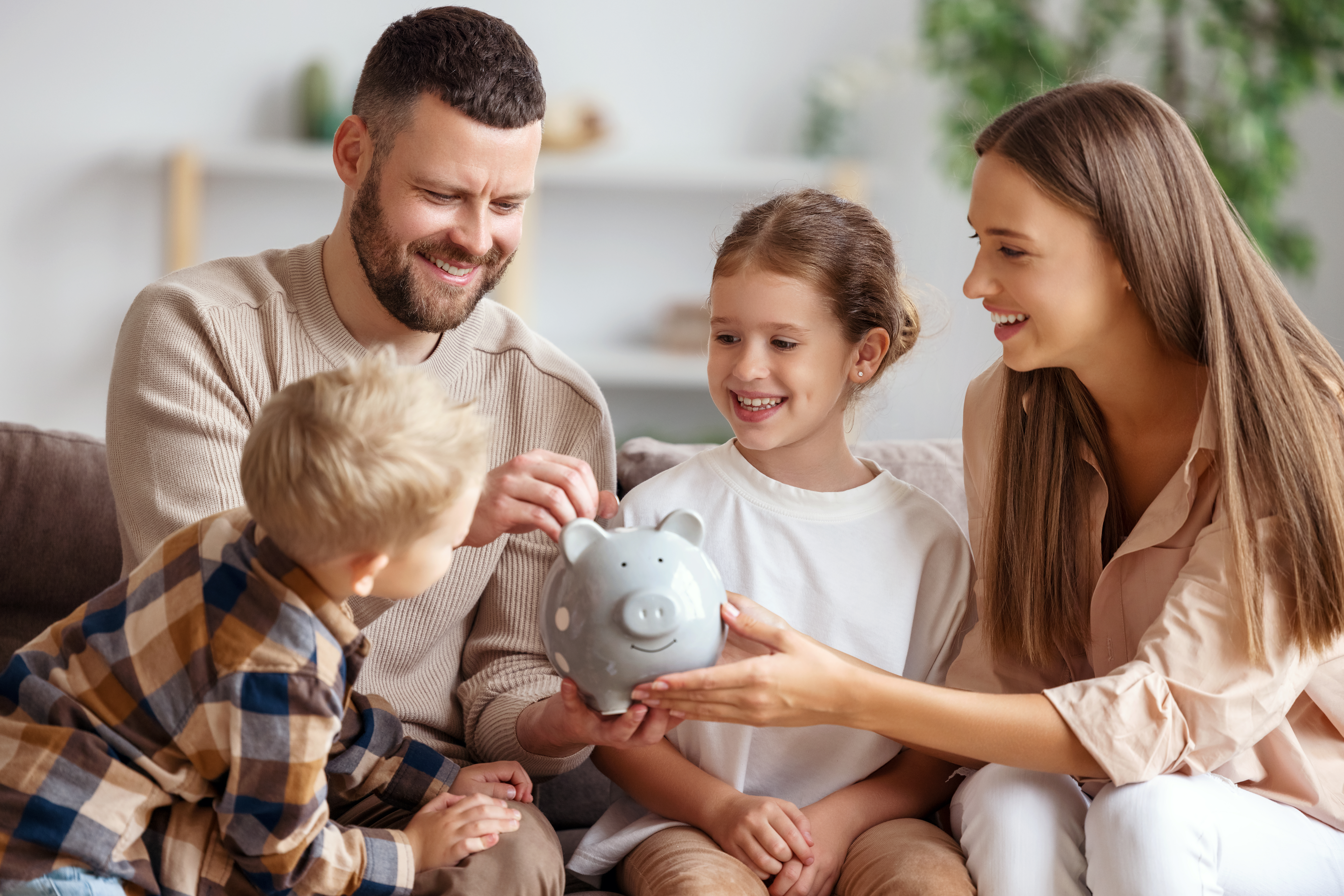 Parents putting coins into piggy bank with daughter and son