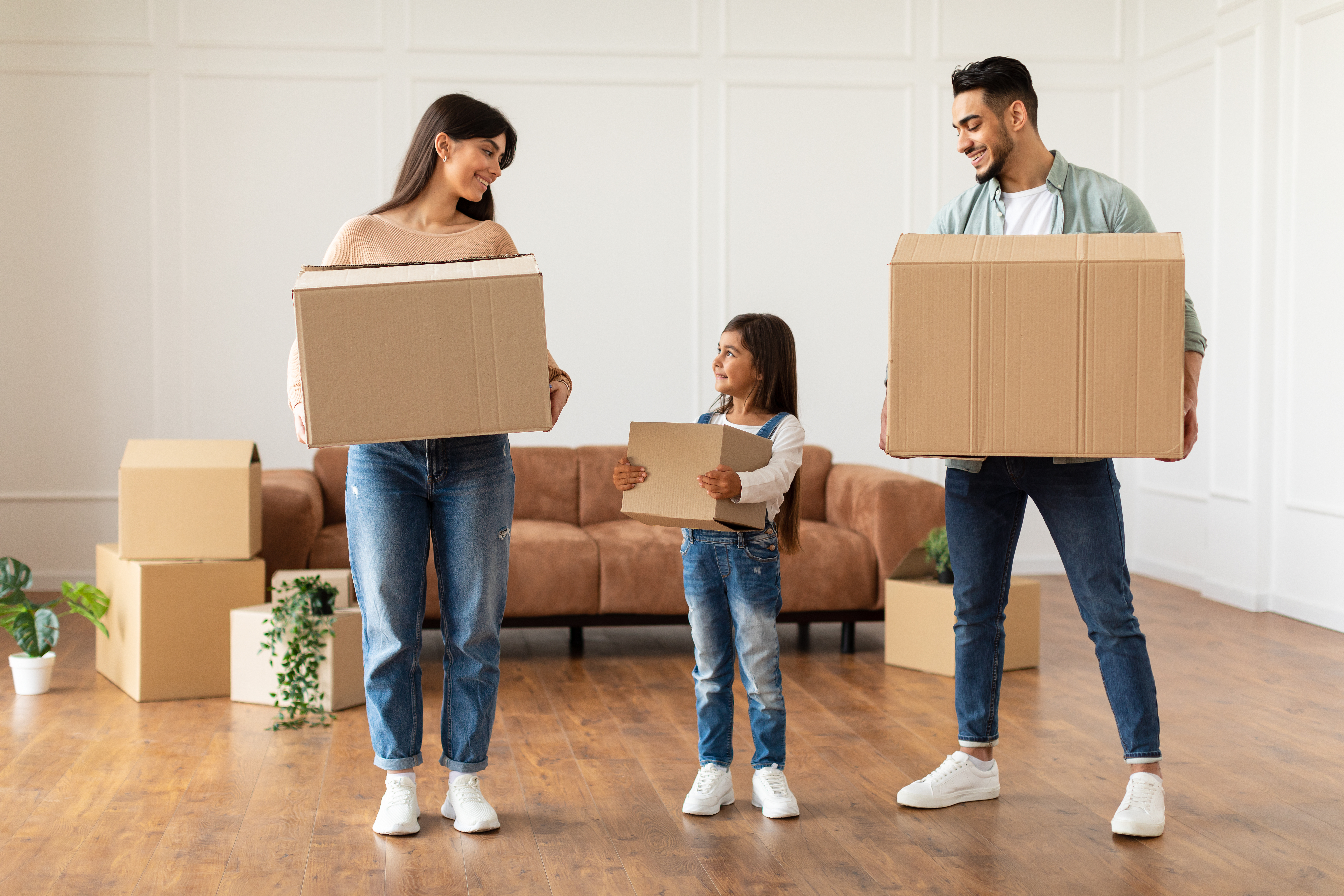 Parents and child holding moving boxes